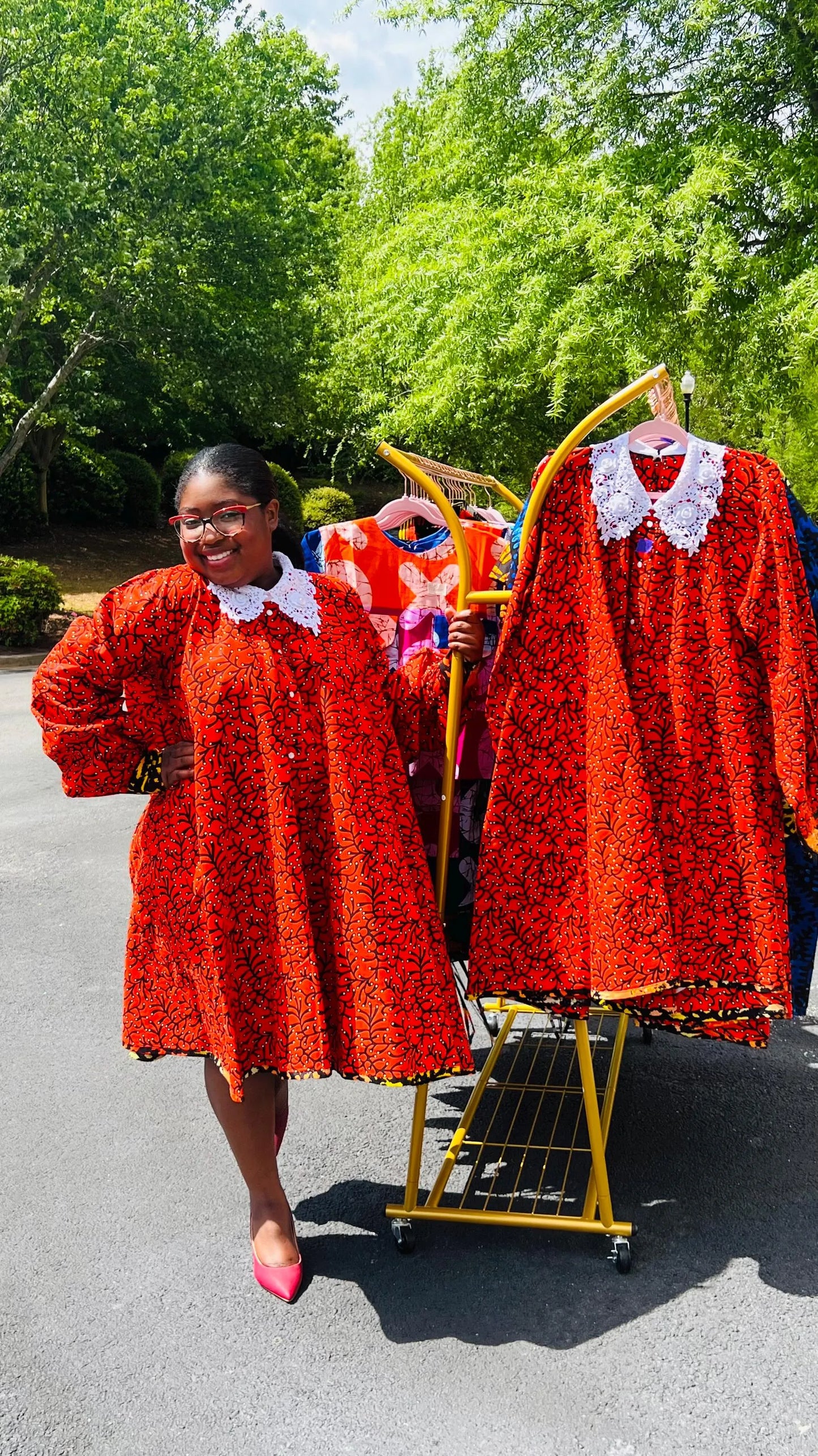 Woman wearing a vibrant Ankara full-circle A-line dress with a lace collar, standing outdoors.