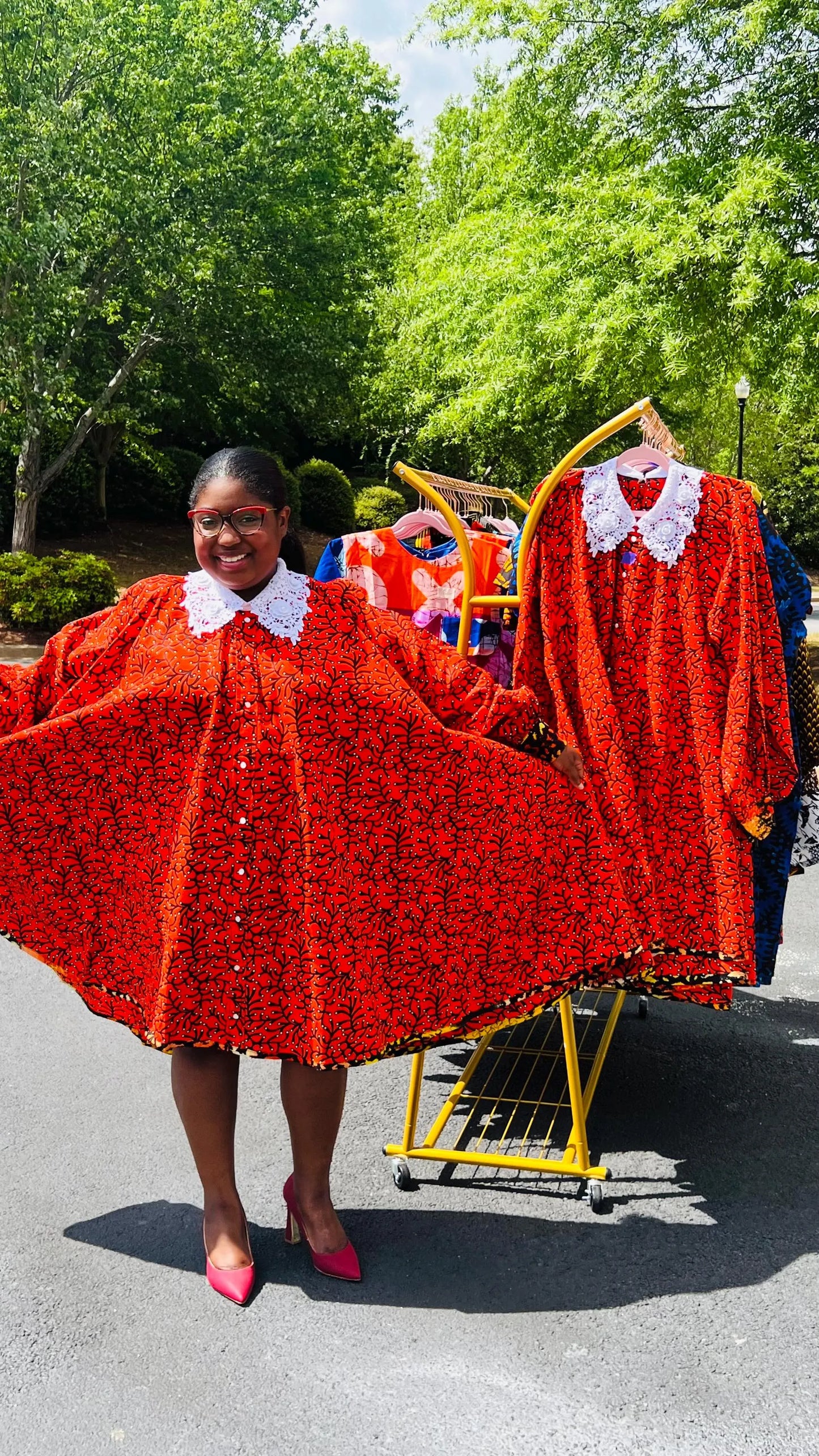 Woman wearing a vibrant Ankara full-circle A-line dress with a lace collar, standing outdoors.