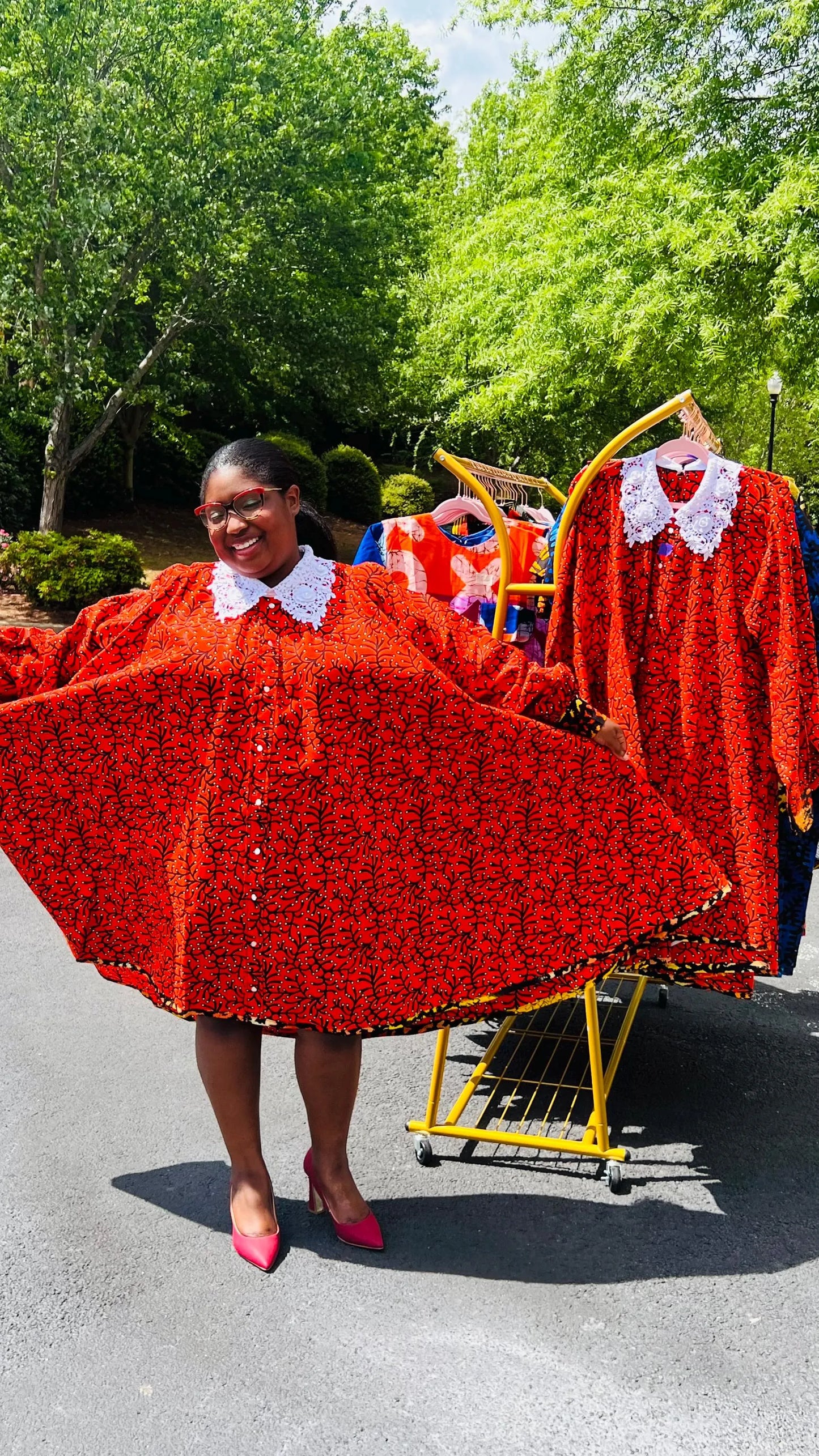 Woman wearing a vibrant Ankara full-circle A-line dress with a lace collar, standing outdoors.