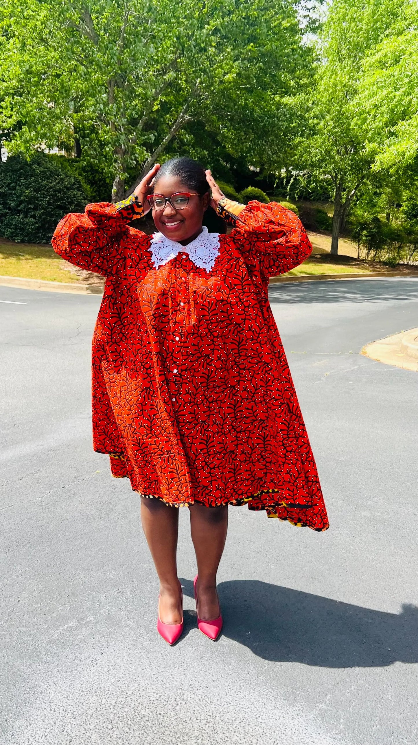 Woman wearing a vibrant Ankara full-circle A-line dress with a lace collar, standing outdoors.