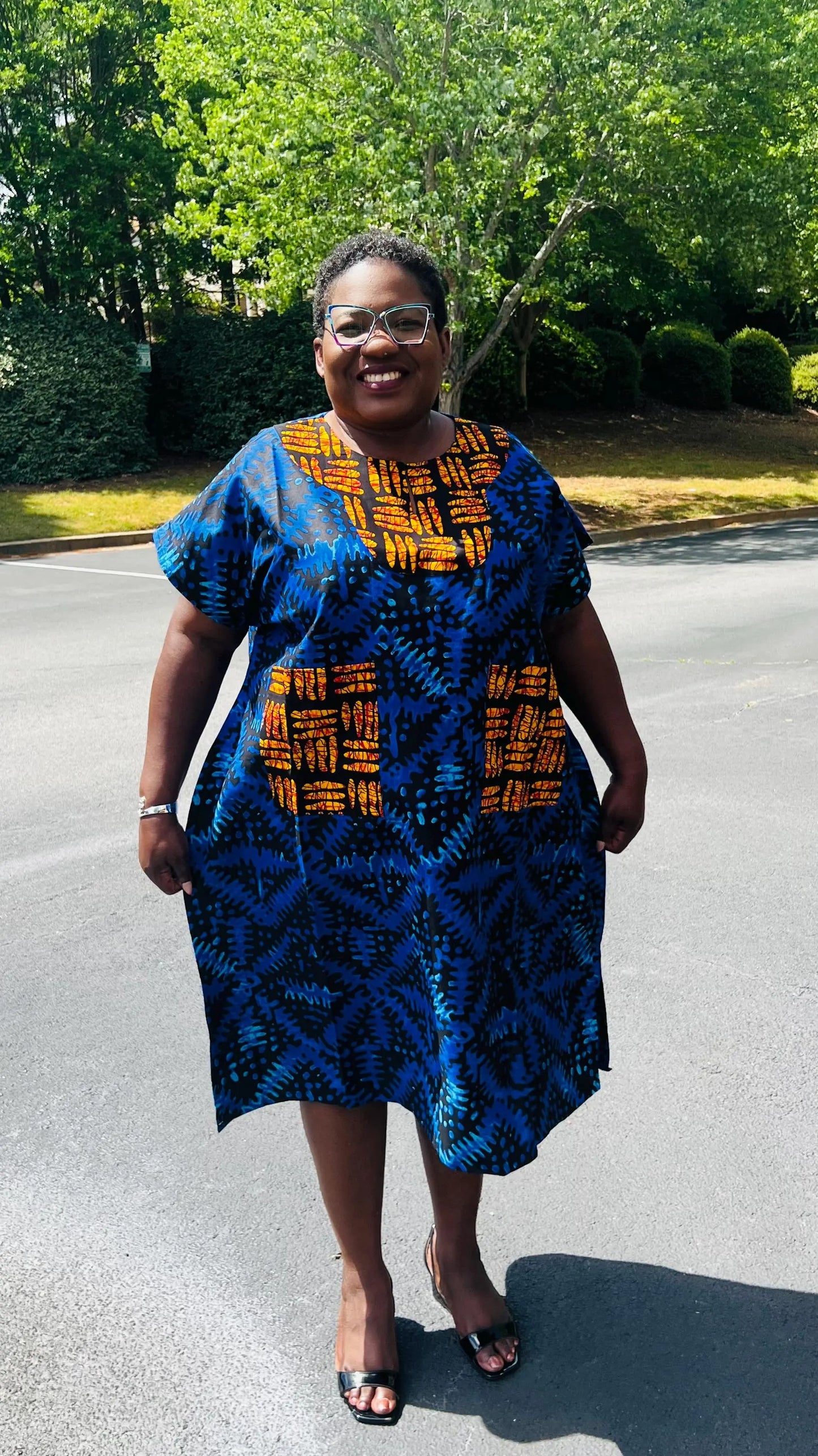 Woman wearing a floor-length Ankara Bubu gown with wide sleeves, front pockets, and a relaxed fit, standing outdoors.