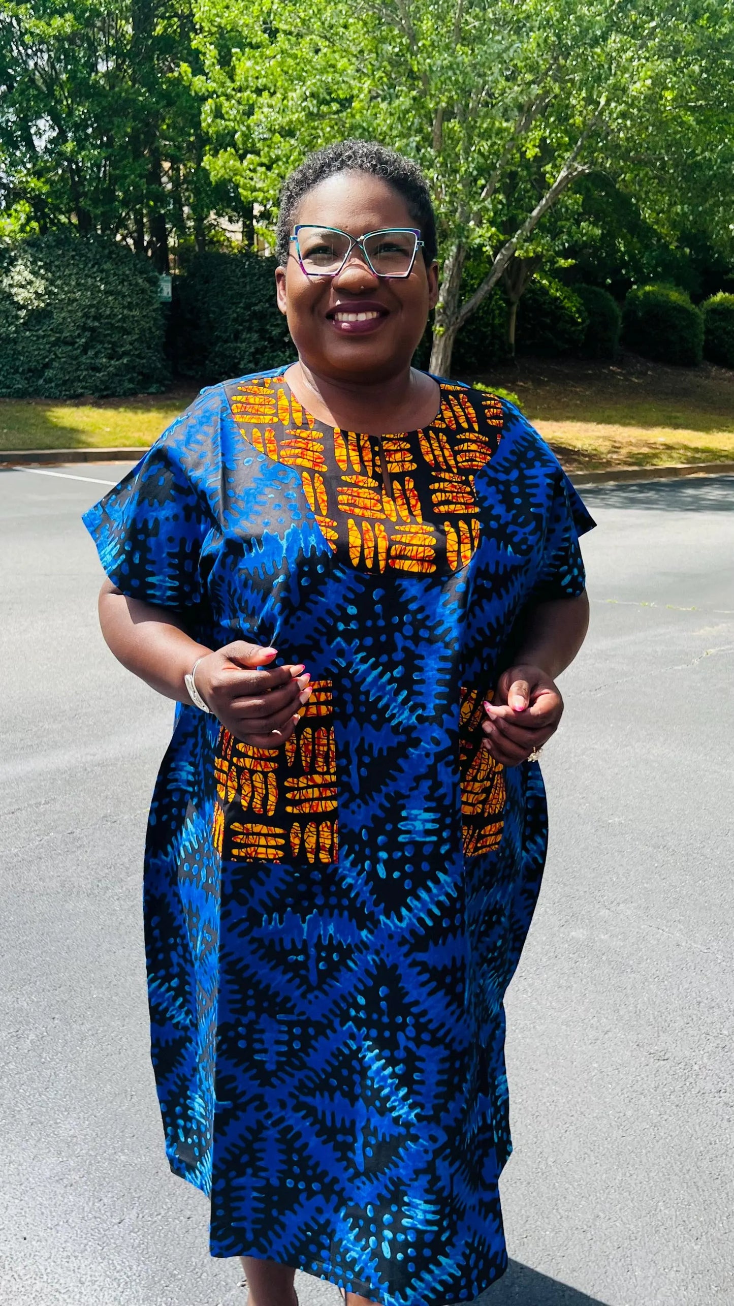 Woman wearing a floor-length Ankara Bubu gown with wide sleeves, front pockets, and a relaxed fit, standing outdoors.