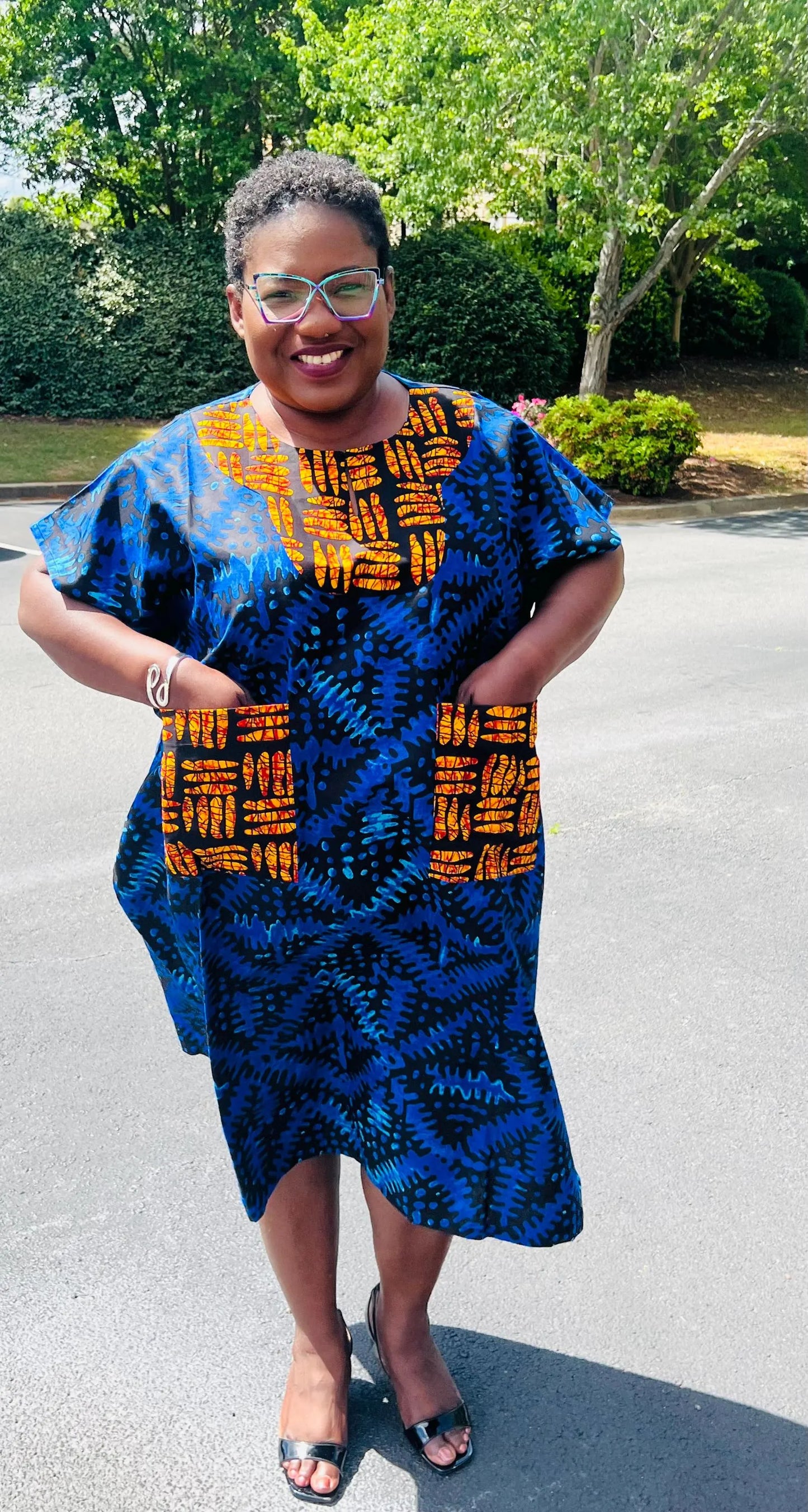 Woman wearing a floor-length Ankara Bubu gown with wide sleeves, front pockets, and a relaxed fit, standing outdoors.
