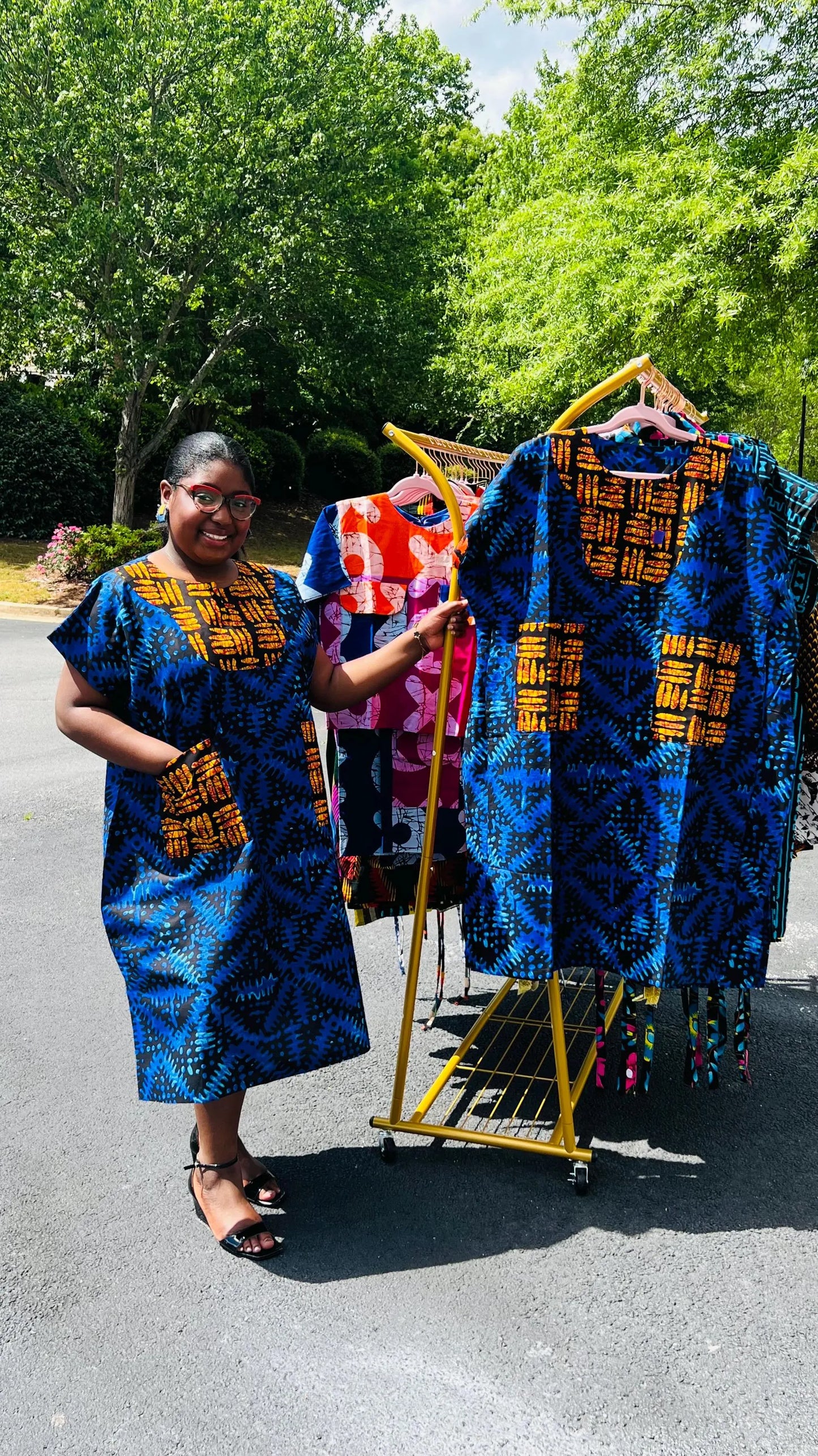 Woman wearing a floor-length Ankara Bubu gown with wide sleeves, front pockets, and a relaxed fit, standing outdoors.