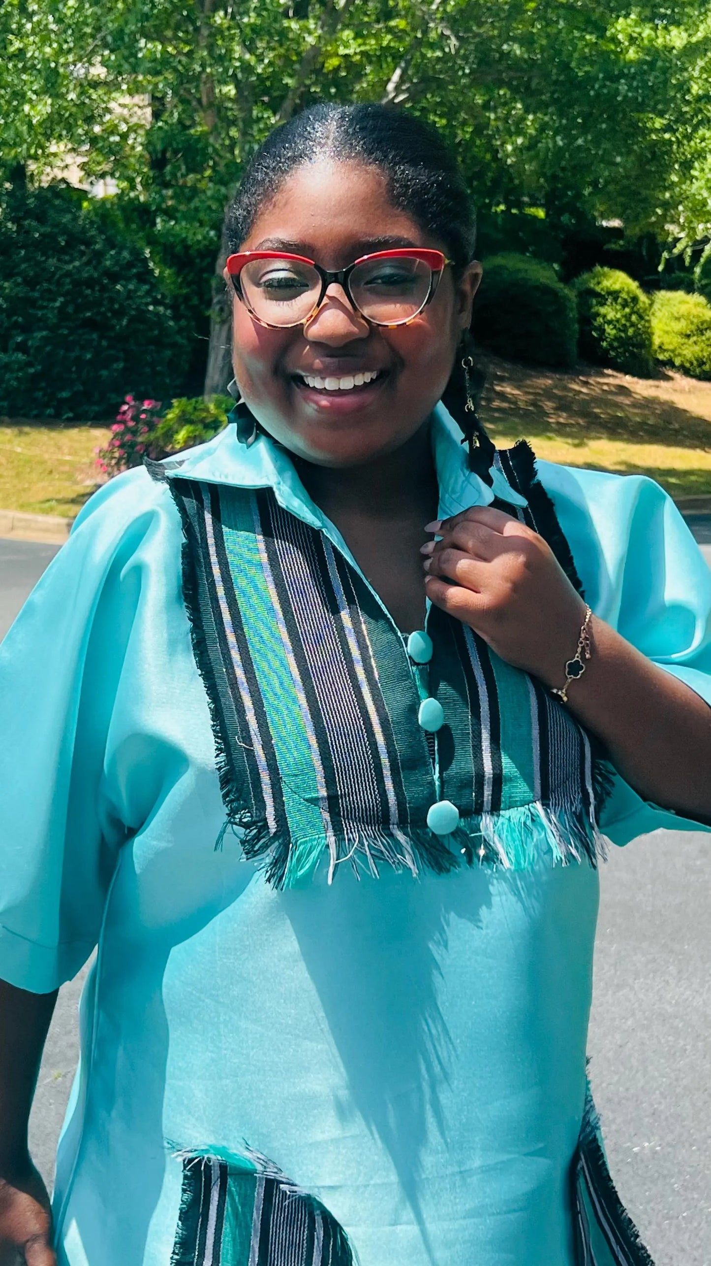 Woman wearing a floor-length Aso Oke dress with vibrant African prints, featuring a fitted bodice and flared skirt, posing outdoors.