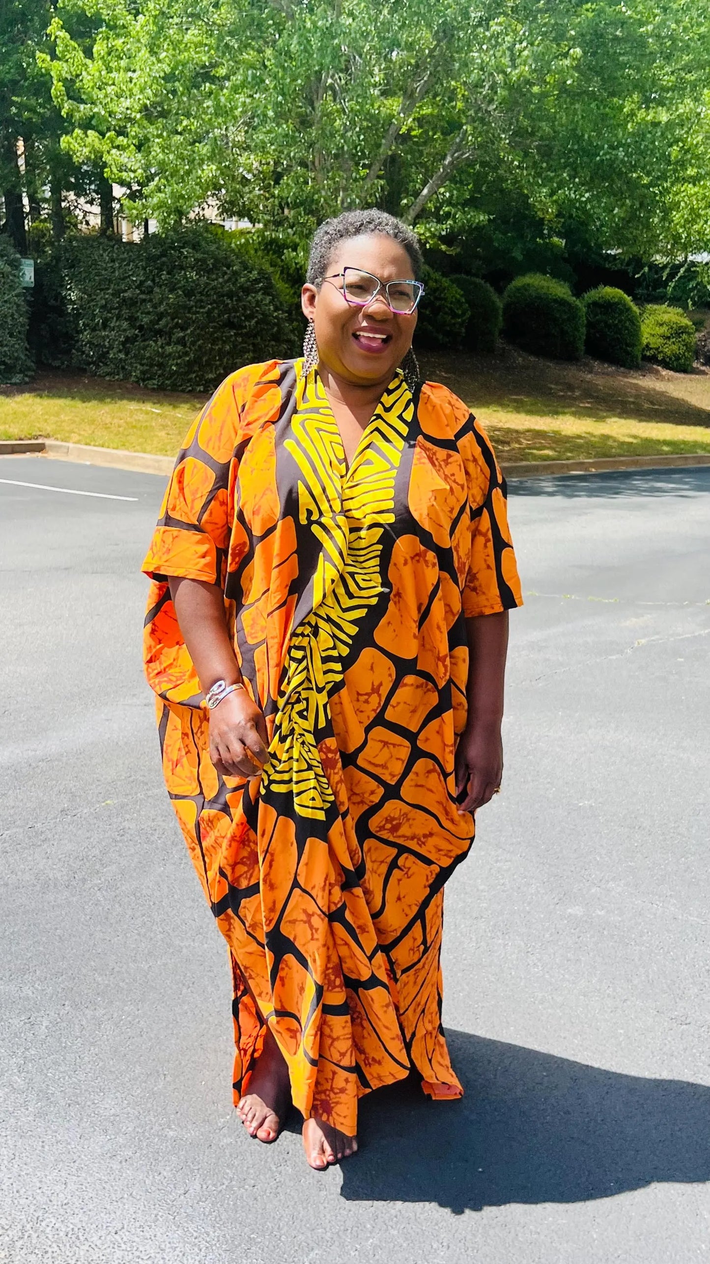 Woman wearing a vibrant, floor-length Ankara Bubu gown with wide sleeves and a relaxed fit, standing outdoors.