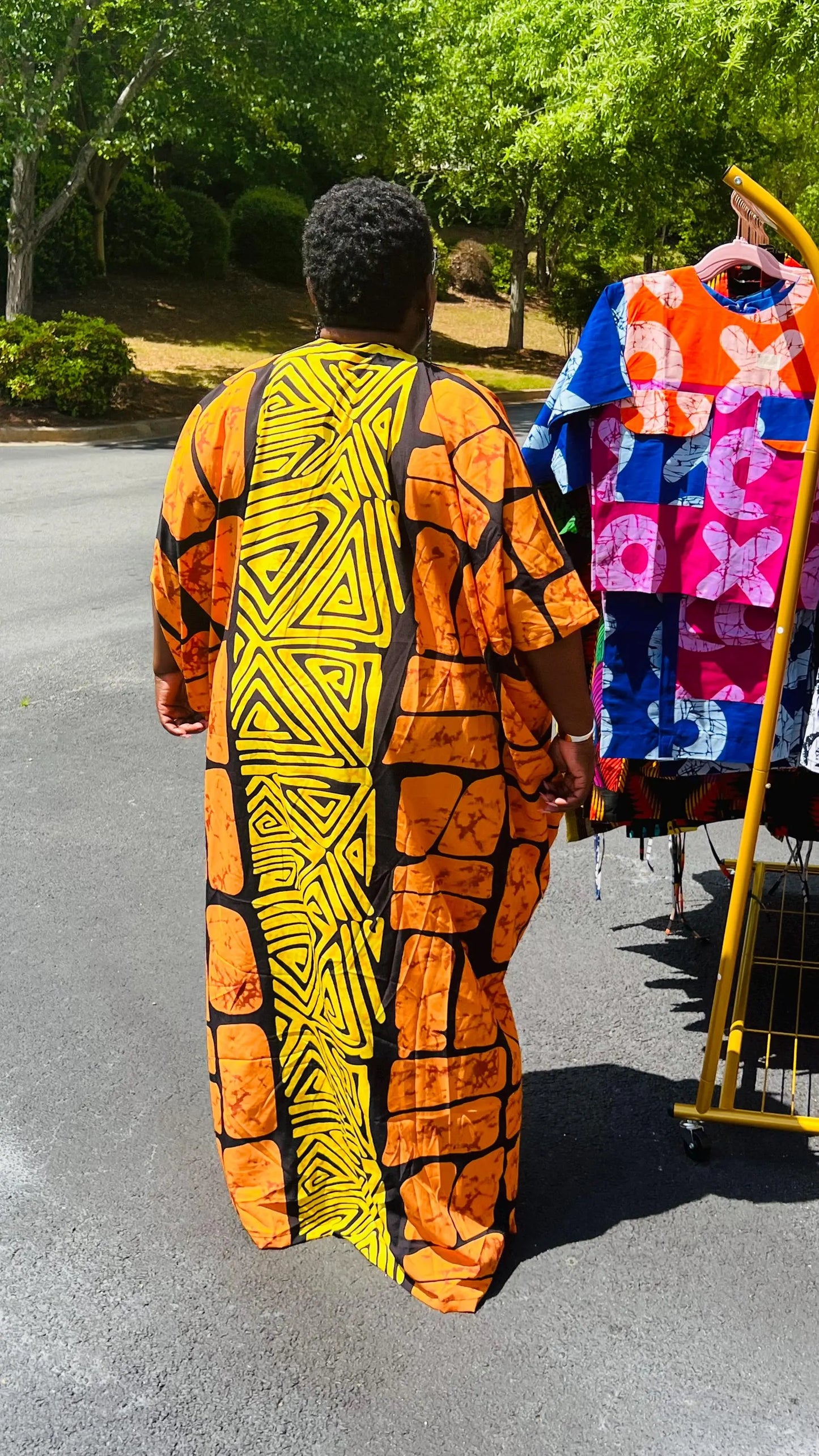 Woman wearing a vibrant, floor-length Ankara Bubu gown with wide sleeves and a relaxed fit, standing outdoors.