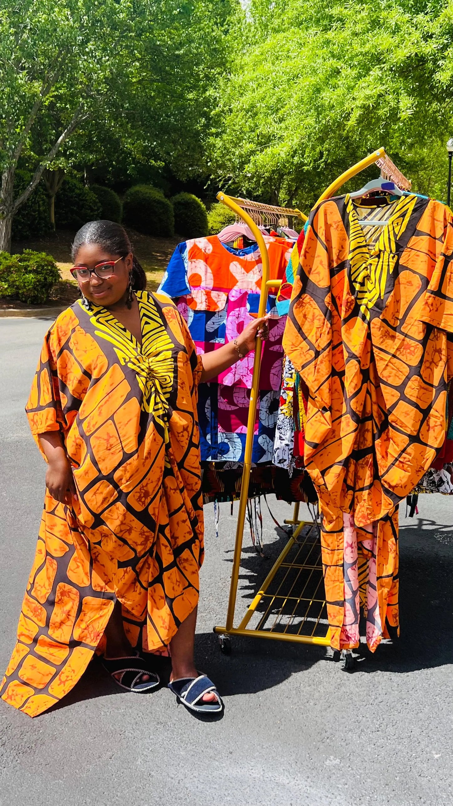 Woman wearing a vibrant, floor-length Ankara Bubu gown with wide sleeves and a relaxed fit, standing outdoors.