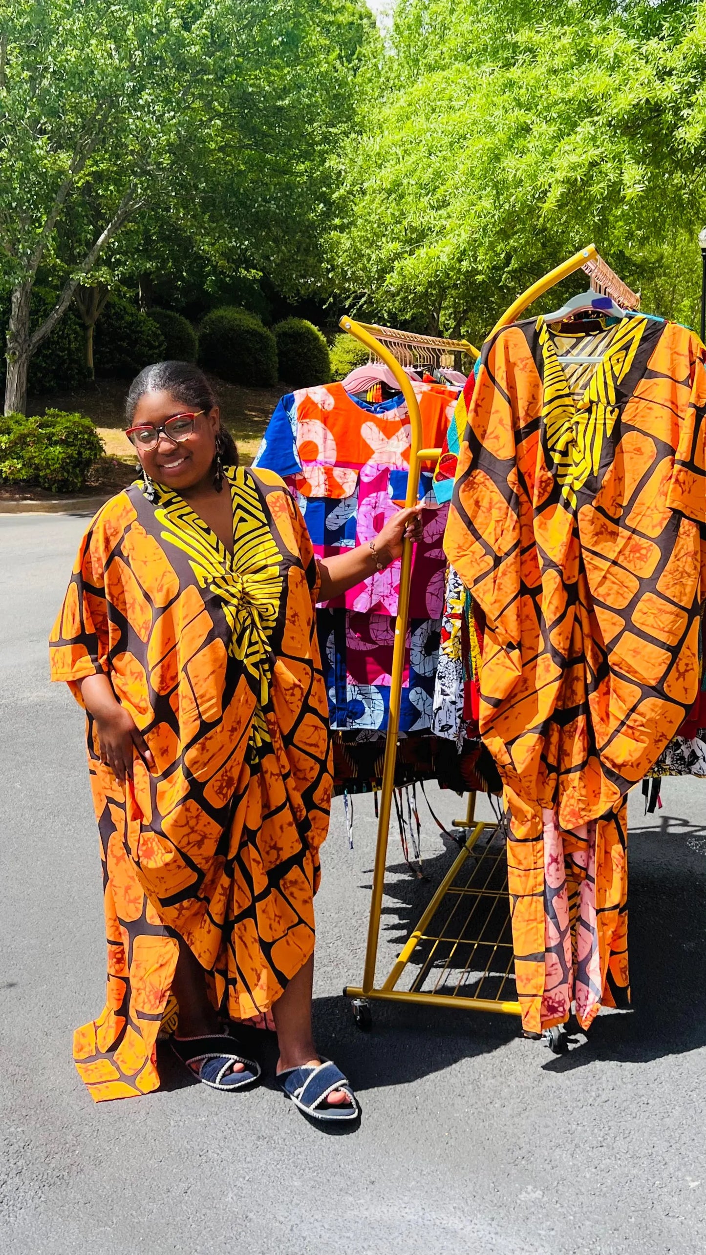 Woman wearing a vibrant, floor-length Ankara Bubu gown with wide sleeves and a relaxed fit, standing outdoors.