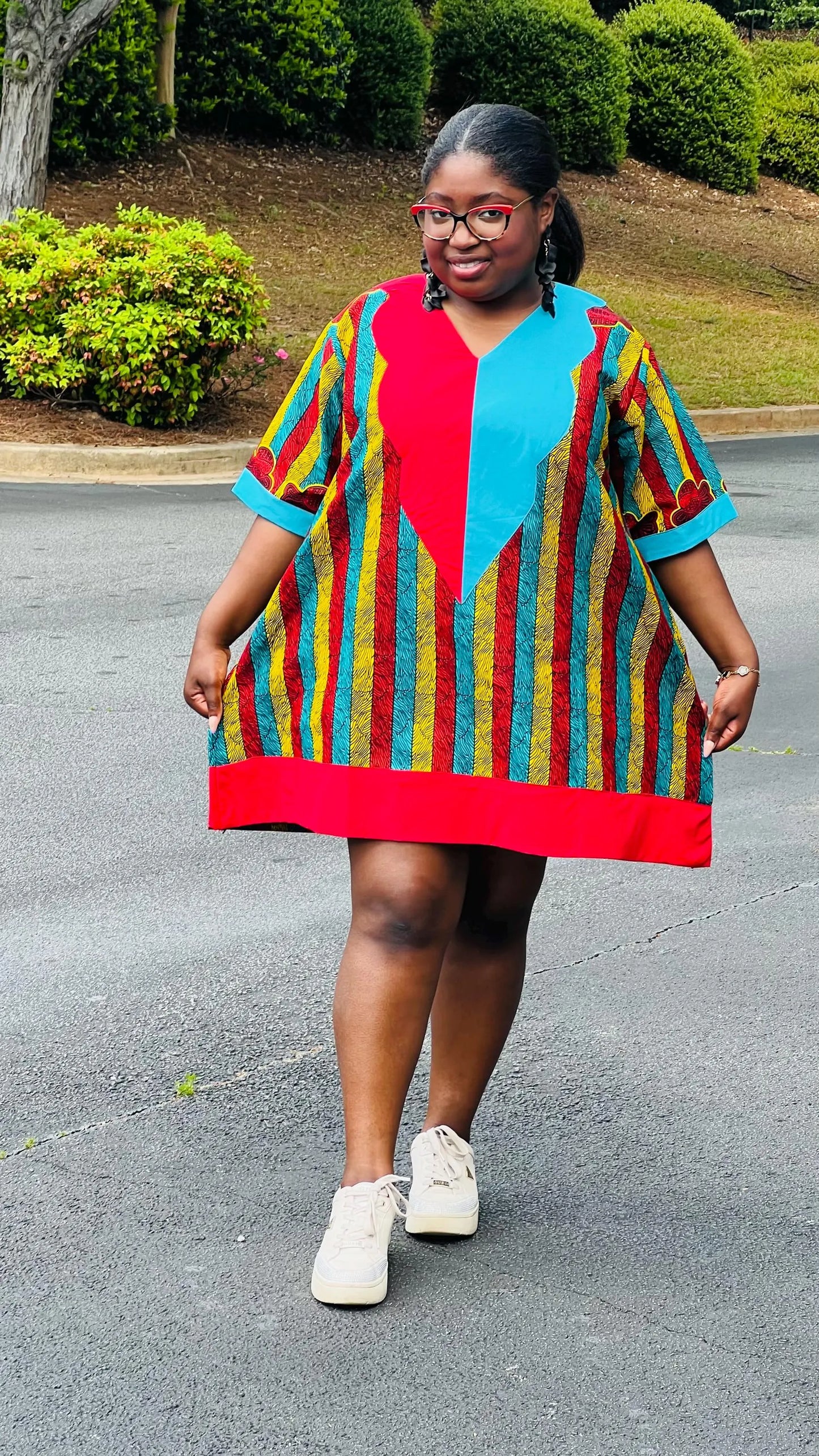 Woman wearing a vibrant African Ankara print mini dress with short sleeves and a flattering A-line silhouette, standing outdoors.