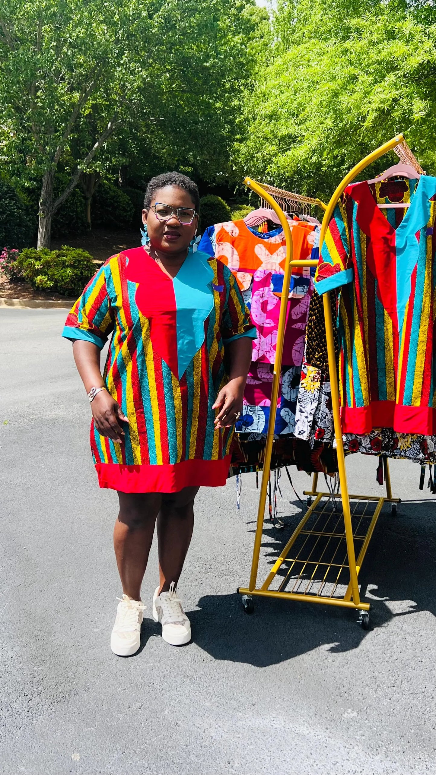 Woman wearing a vibrant African Ankara print mini dress with short sleeves and a flattering A-line silhouette, standing outdoors.