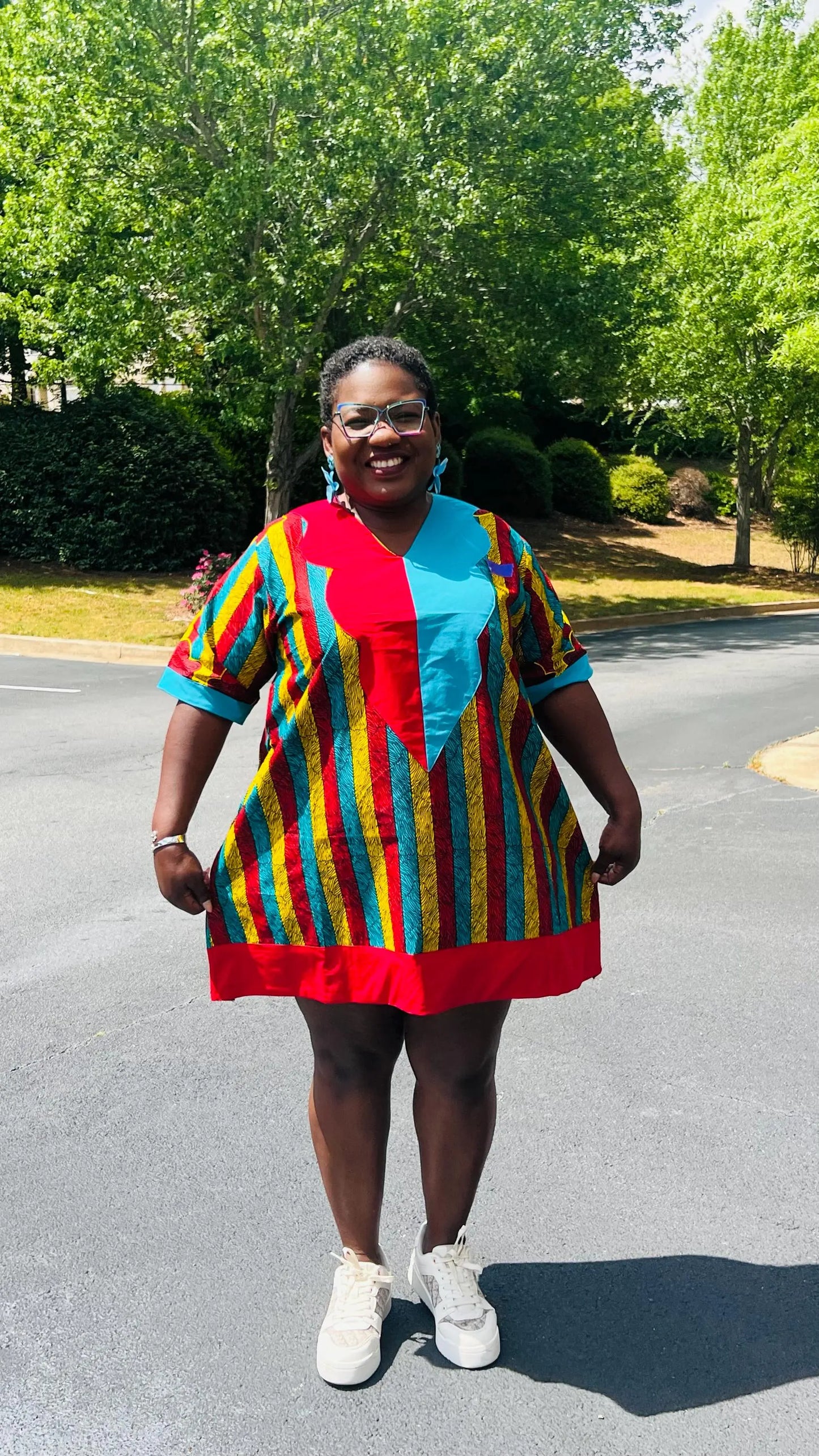 Woman wearing a vibrant African Ankara print mini dress with short sleeves and a flattering A-line silhouette, standing outdoors.