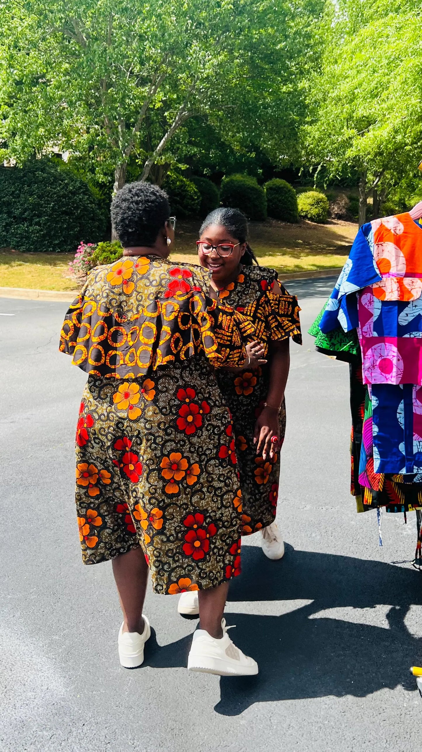 Woman wearing a reversible Ankara dress with open shoulders, ruffled A-line skirt, and front zipper, standing outdoors.