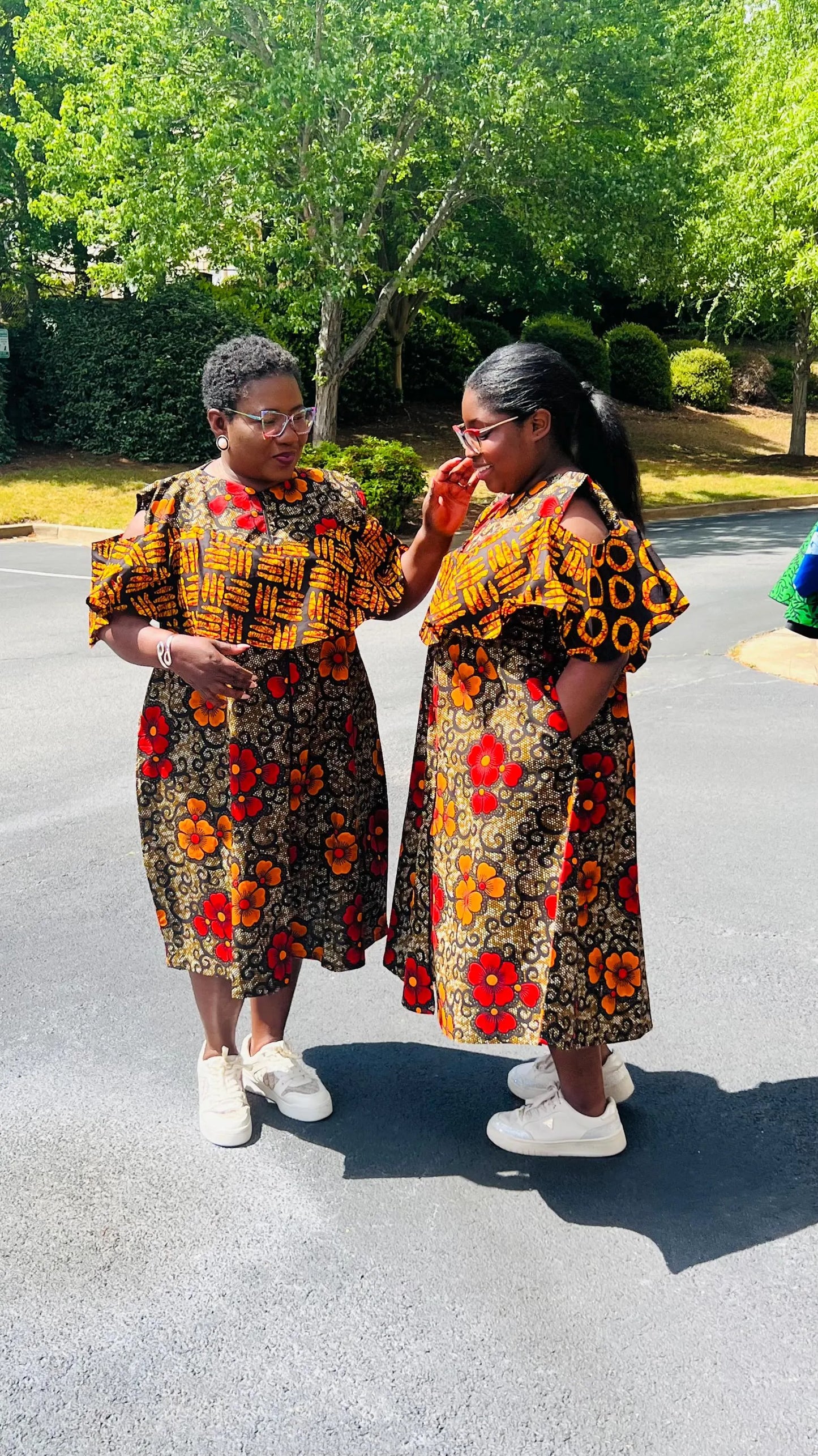 Woman wearing a reversible Ankara dress with open shoulders, ruffled A-line skirt, and front zipper, standing outdoors.