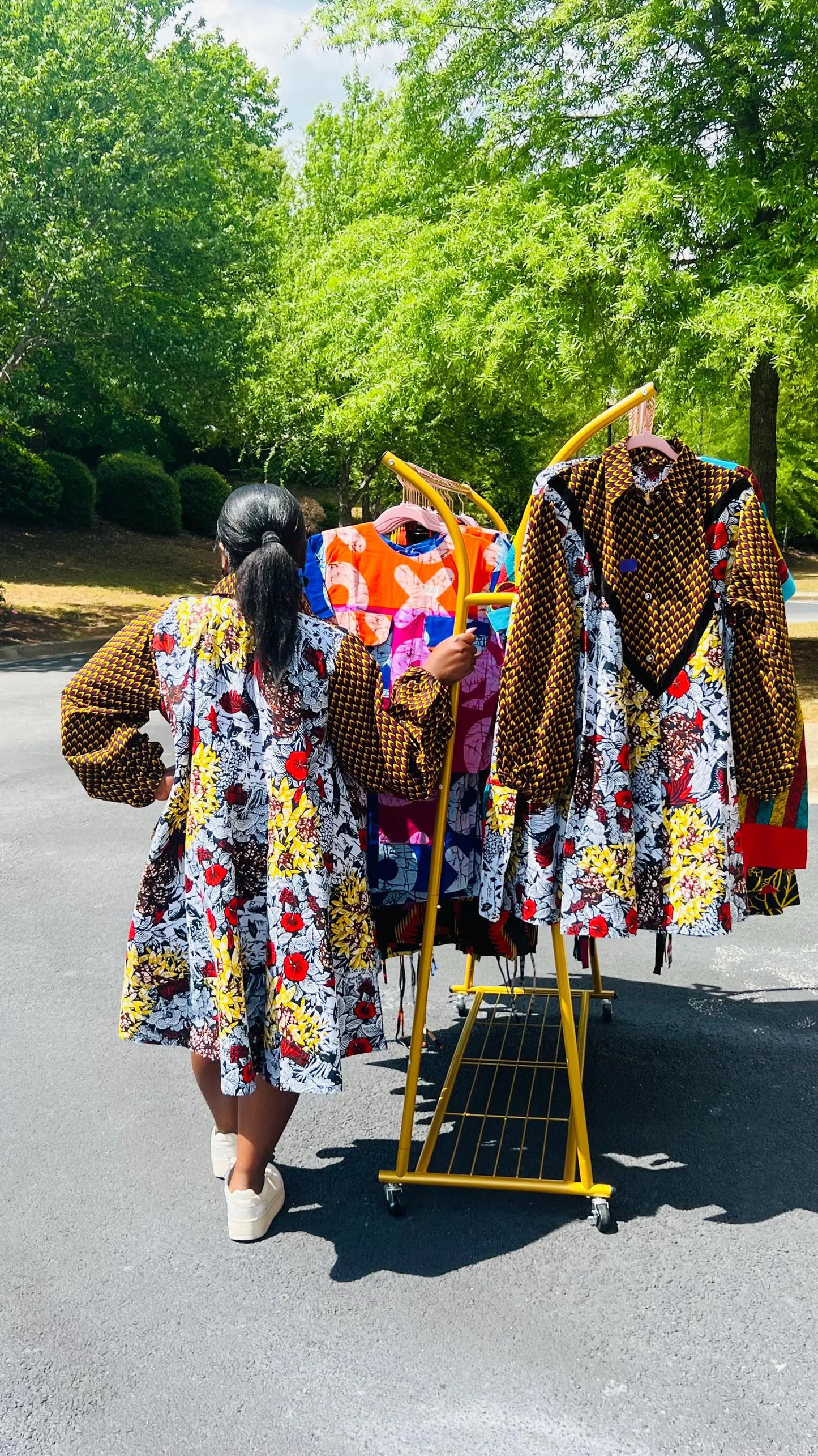 Woman wearing a vibrant Ankara A-line dress with puff sleeves, velvet button-up front, and knee-length hem, standing outdoors.