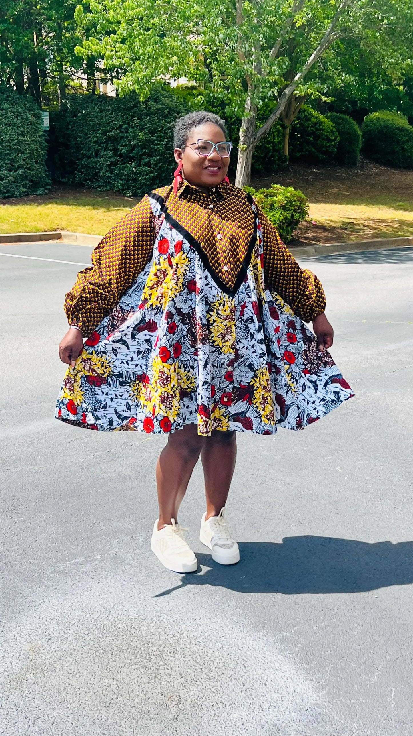 Woman wearing a vibrant Ankara A-line dress with puff sleeves, velvet button-up front, and knee-length hem, standing outdoors.