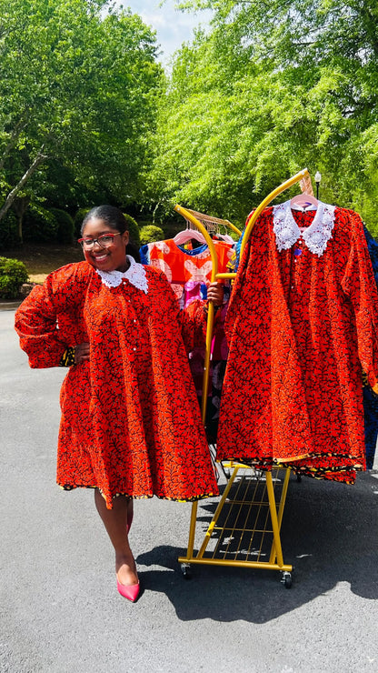 Woman wearing a vibrant Ankara full-circle A-line dress with a lace collar, standing outdoors.