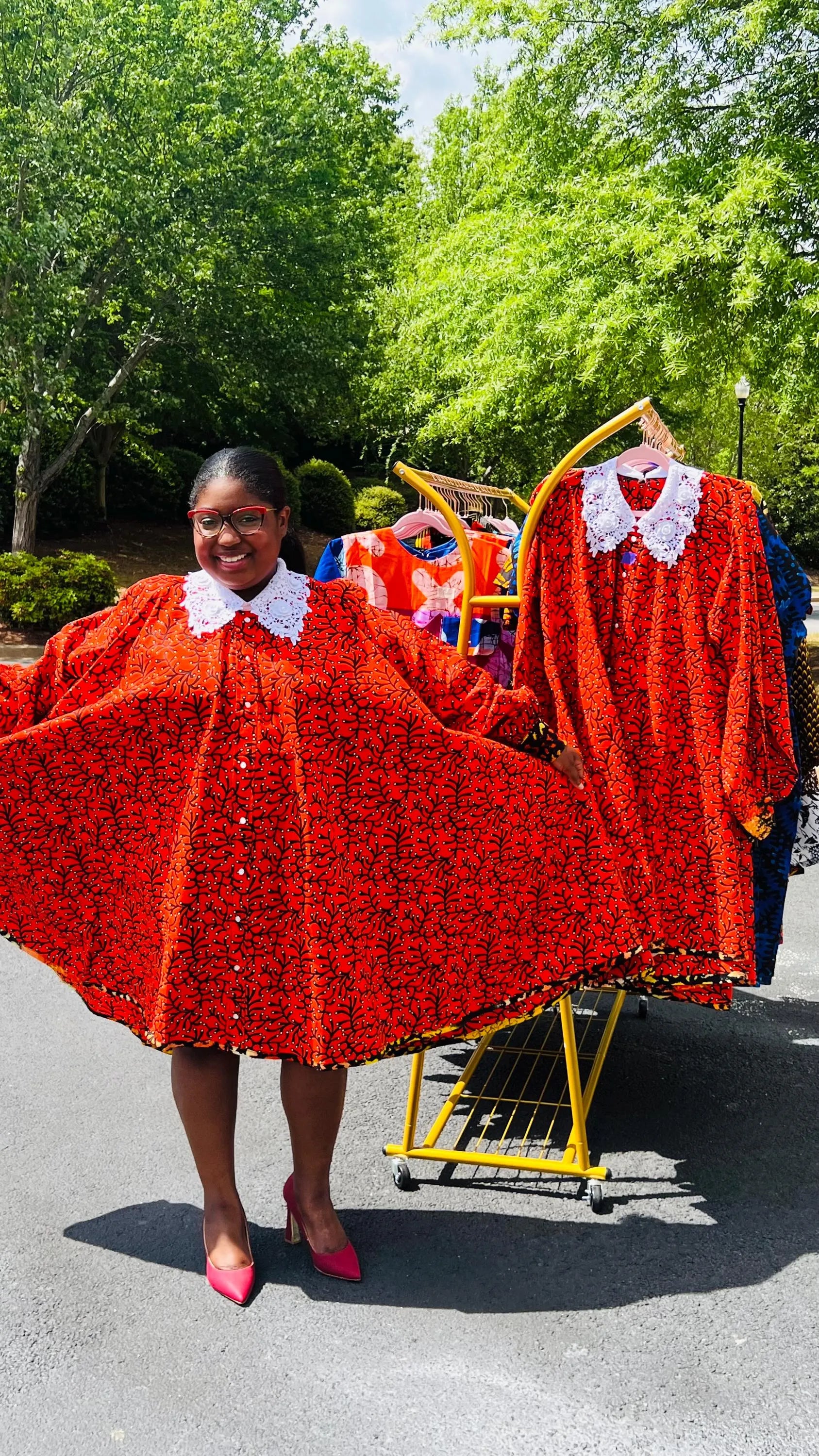 Woman wearing a vibrant Ankara full-circle A-line dress with a lace collar, standing outdoors.