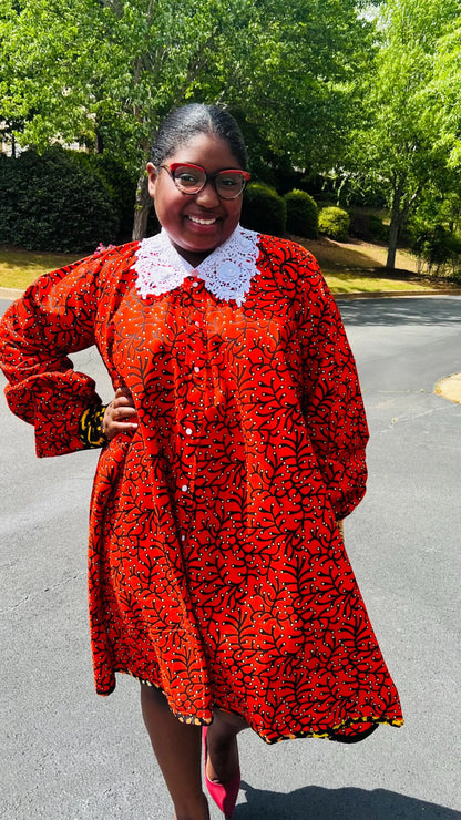 Woman wearing a vibrant Ankara full-circle A-line dress with a lace collar, standing outdoors.