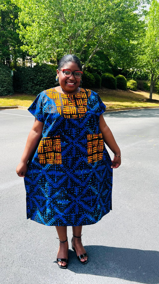 Woman wearing a floor-length Ankara Bubu gown with wide sleeves, front pockets, and a relaxed fit, standing outdoors.