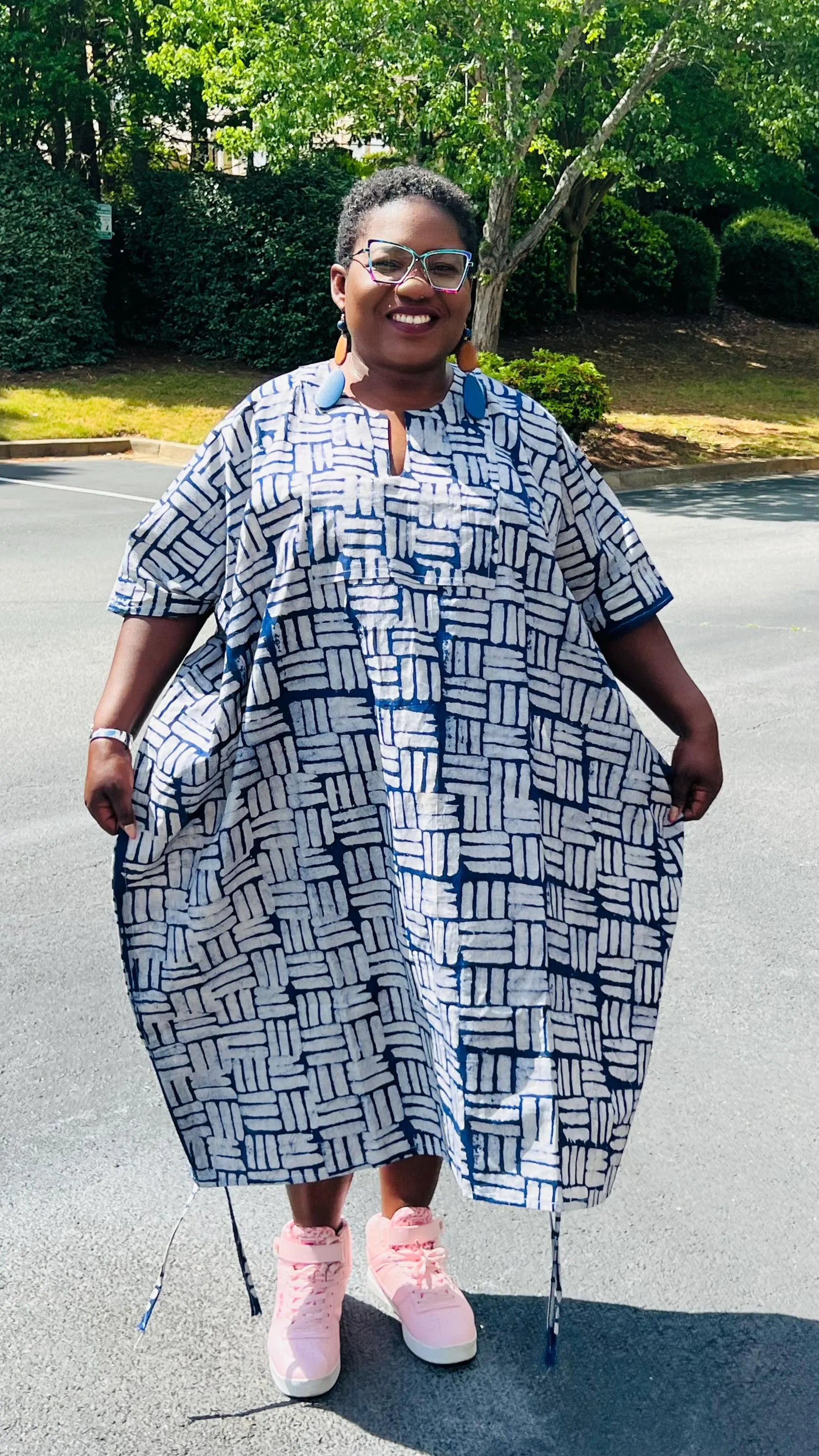 Woman wearing a two-piece African print Adire set with a drawstring Bubu top and matching baggy pants, standing outdoors.