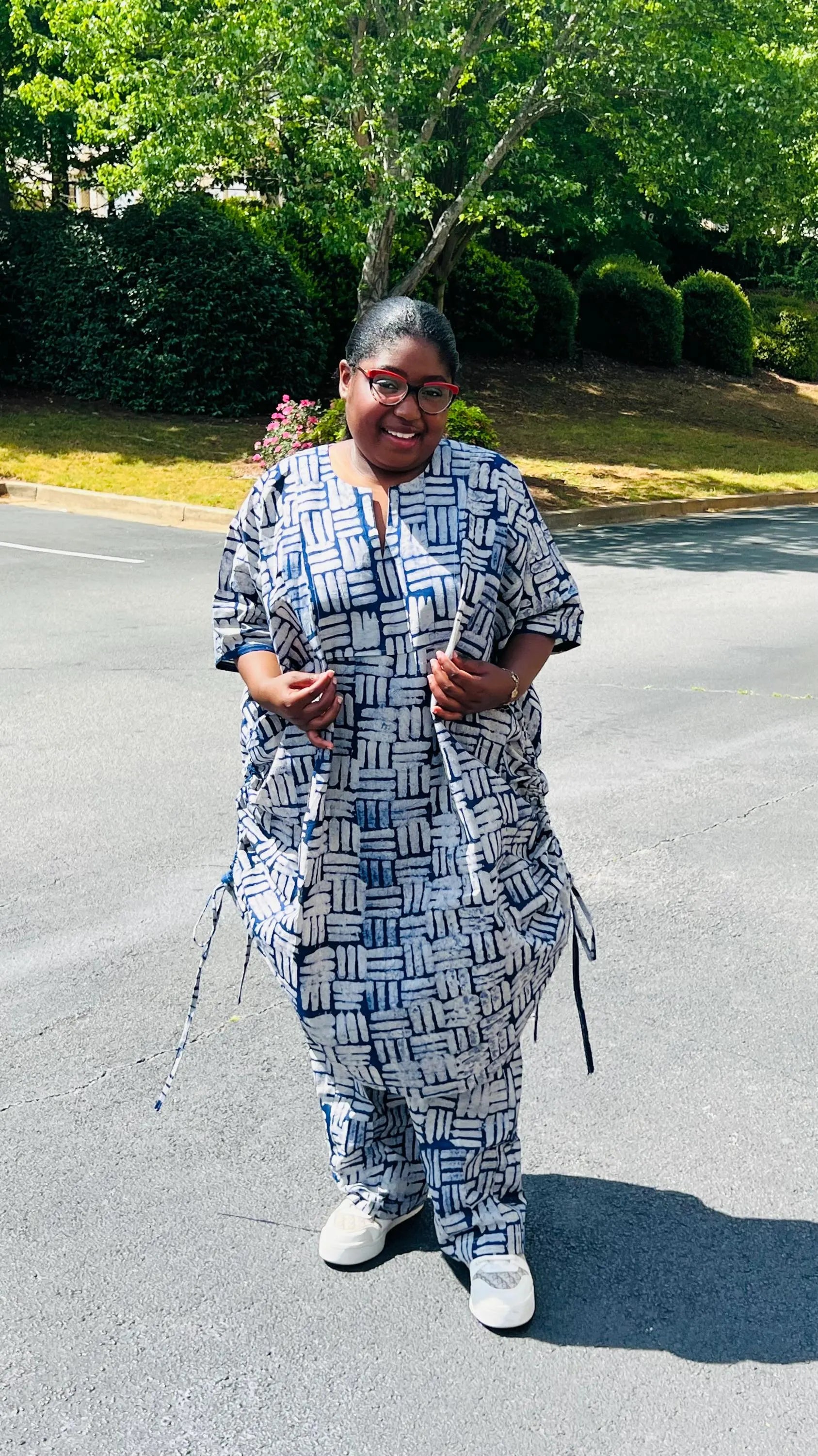 Woman wearing a two-piece African print Adire set with a drawstring Bubu top and matching baggy pants, standing outdoors.