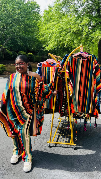 Woman wearing a two-piece African print set featuring an off-shoulder drawstring Bubu top and matching wide-leg pants, standing outdoors.