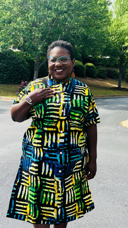 Woman wearing a two-piece Ankara outfit featuring a button-up top and matching baggy pants with an elastic waistband, standing outdoors.