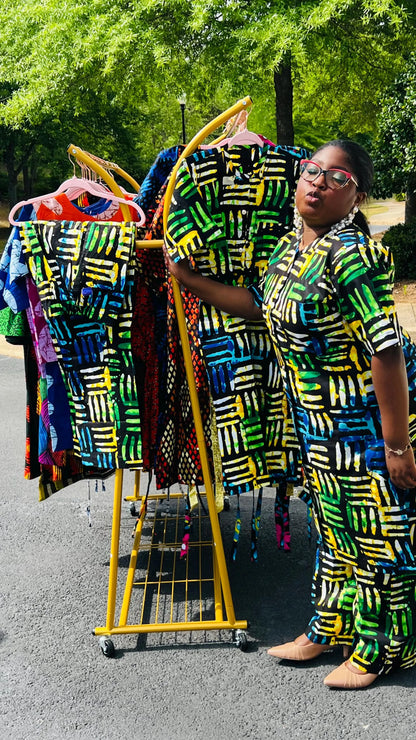 Woman wearing a two-piece Ankara outfit featuring a button-up top and matching baggy pants with an elastic waistband, standing outdoors.