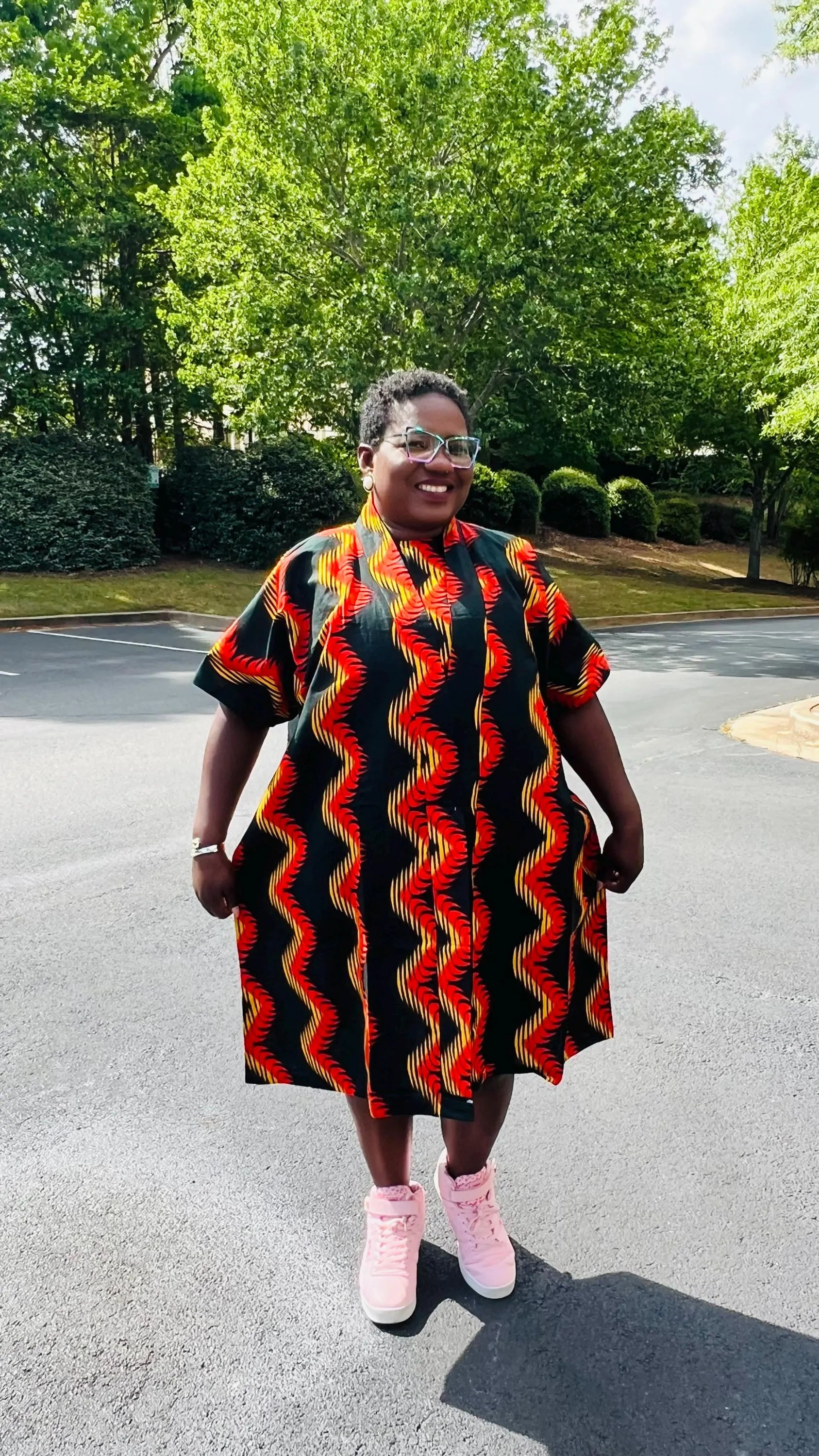 Woman wearing a three-piece Ankara ensemble featuring a fitted top, wide-leg pants, and a flowing kimono-style jacket, standing outdoors.