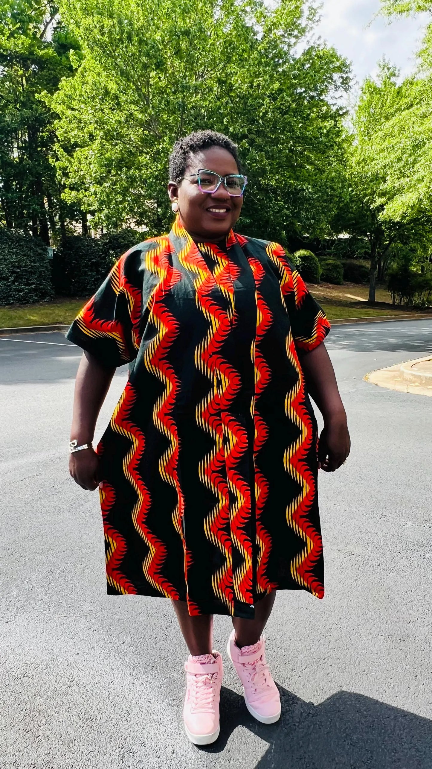 Woman wearing a three-piece Ankara ensemble featuring a fitted top, wide-leg pants, and a flowing kimono-style jacket, standing outdoors.