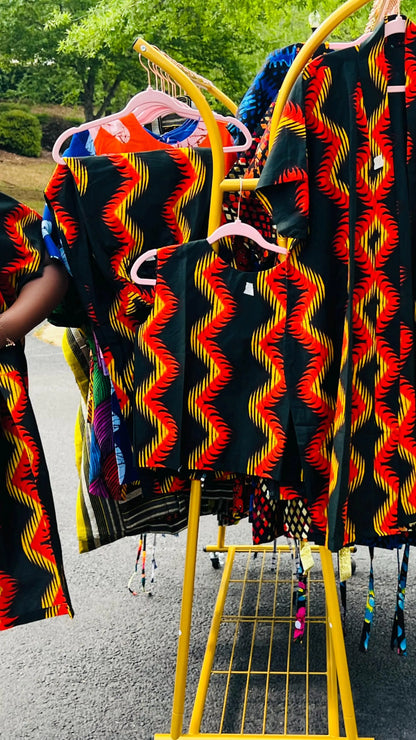Woman wearing a three-piece Ankara ensemble featuring a fitted top, wide-leg pants, and a flowing kimono-style jacket, standing outdoors.