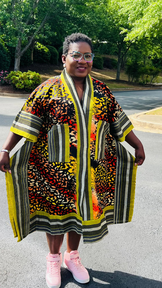 Woman wearing a two-piece African print ensemble featuring a cotton Ankara kimono jacket with Aso Oke accents and matching elastic waist pants, standing outdoors.