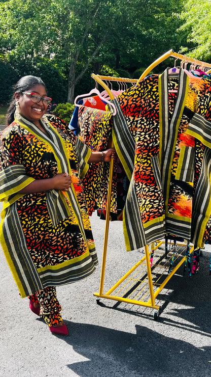 Woman wearing a two-piece African print ensemble featuring a cotton Ankara kimono jacket with Aso Oke accents and matching elastic waist pants, standing outdoors.