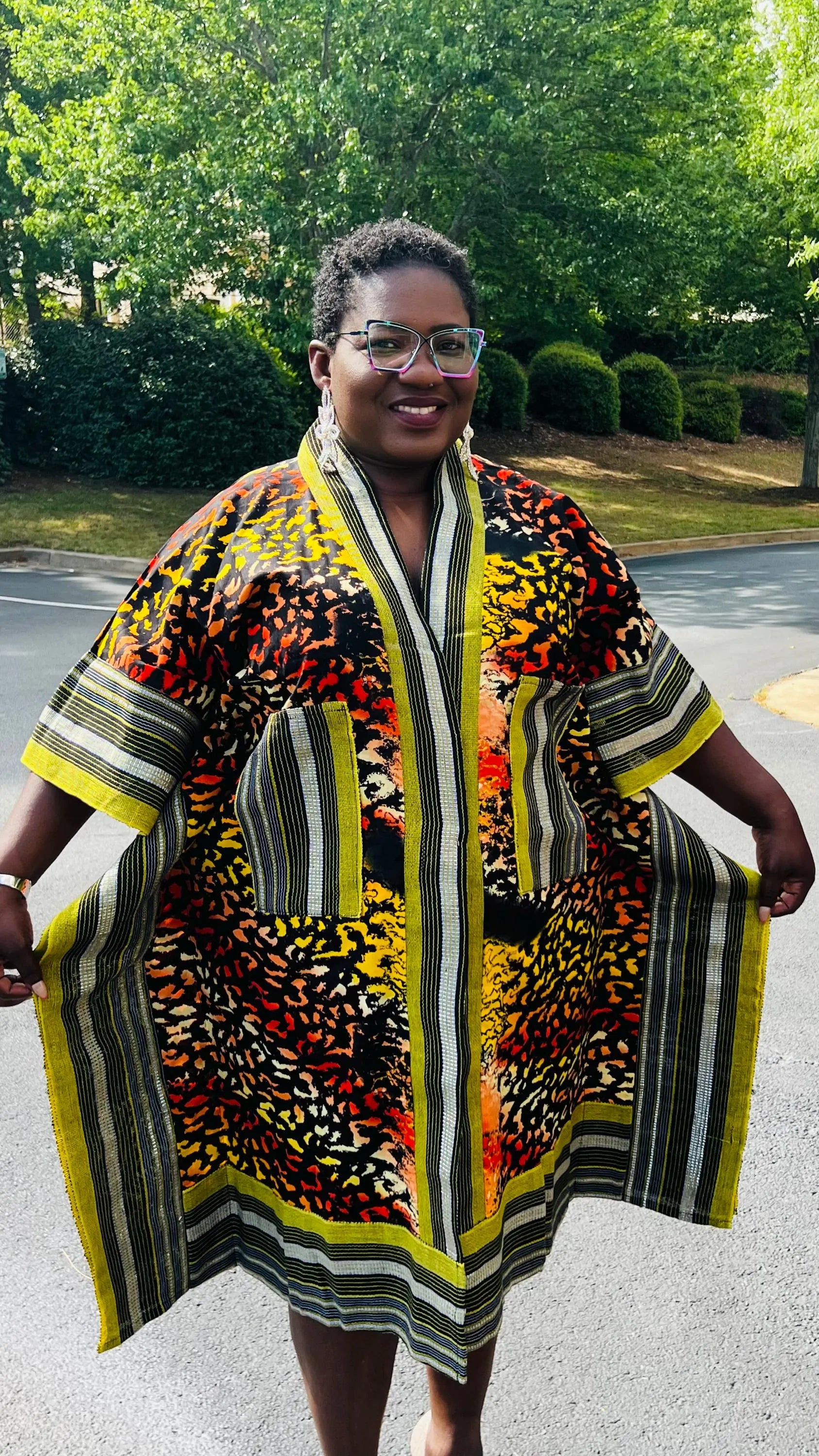 Woman wearing a two-piece African print ensemble featuring a cotton Ankara kimono jacket with Aso Oke accents and matching elastic waist pants, standing outdoors.