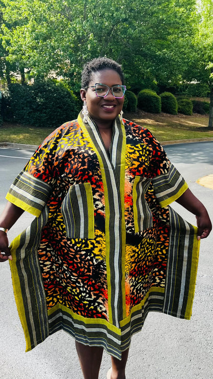 Woman wearing a two-piece African print ensemble featuring a cotton Ankara kimono jacket with Aso Oke accents and matching elastic waist pants, standing outdoors.