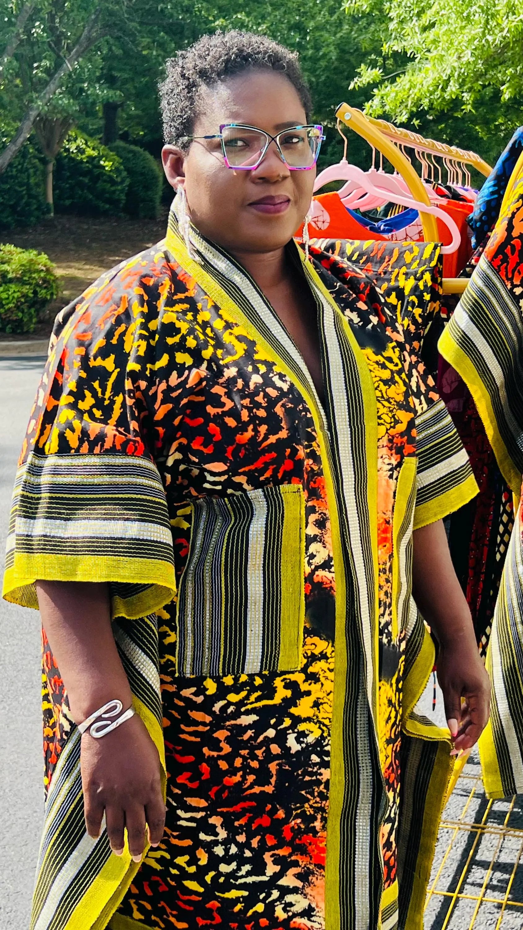 Woman wearing a two-piece African print ensemble featuring a cotton Ankara kimono jacket with Aso Oke accents and matching elastic waist pants, standing outdoors.