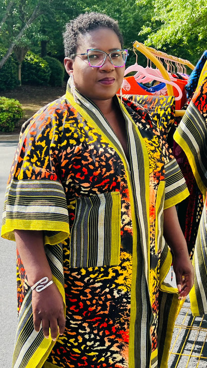 Woman wearing a two-piece African print ensemble featuring a cotton Ankara kimono jacket with Aso Oke accents and matching elastic waist pants, standing outdoors.