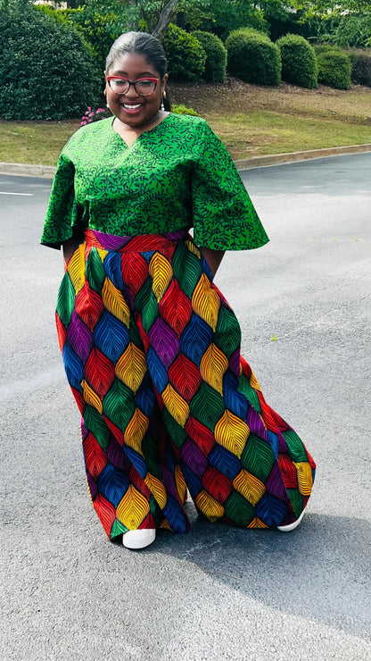 Woman wearing a vibrant two-piece Ankara outfit featuring a flare-sleeve top and matching baggy pants, standing outdoors.