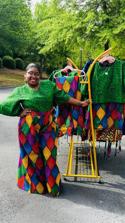 Woman wearing a vibrant two-piece Ankara outfit featuring a flare-sleeve top and matching baggy pants, standing outdoors.