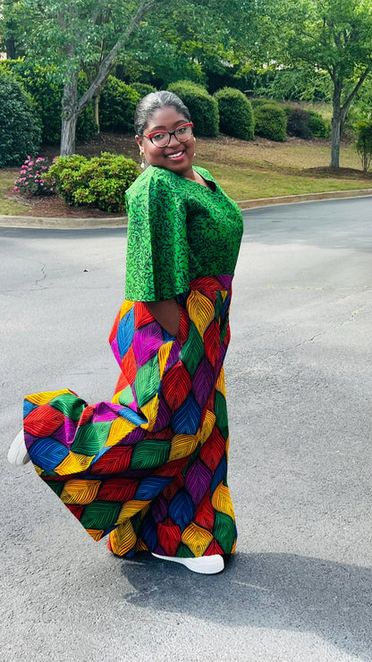 Woman wearing a vibrant two-piece Ankara outfit featuring a flare-sleeve top and matching baggy pants, standing outdoors.