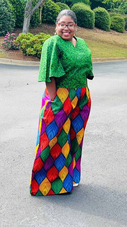 Woman wearing a vibrant two-piece Ankara outfit featuring a flare-sleeve top and matching baggy pants, standing outdoors.