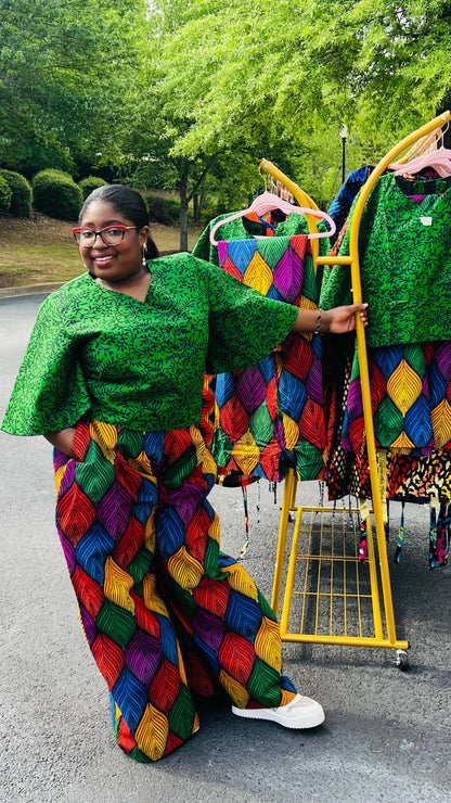 Woman wearing a vibrant two-piece Ankara outfit featuring a flare-sleeve top and matching baggy pants, standing outdoors.