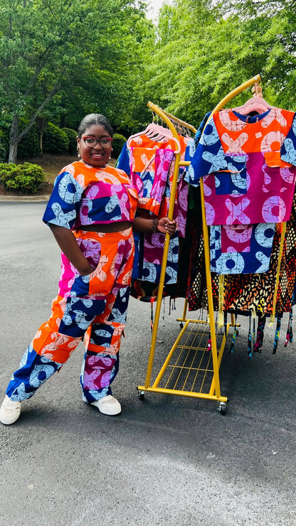 Woman wearing a vibrant two-piece Ankara ensemble featuring a sleeveless crop top and high-waisted cargo pants with multiple pockets, standing outdoors.