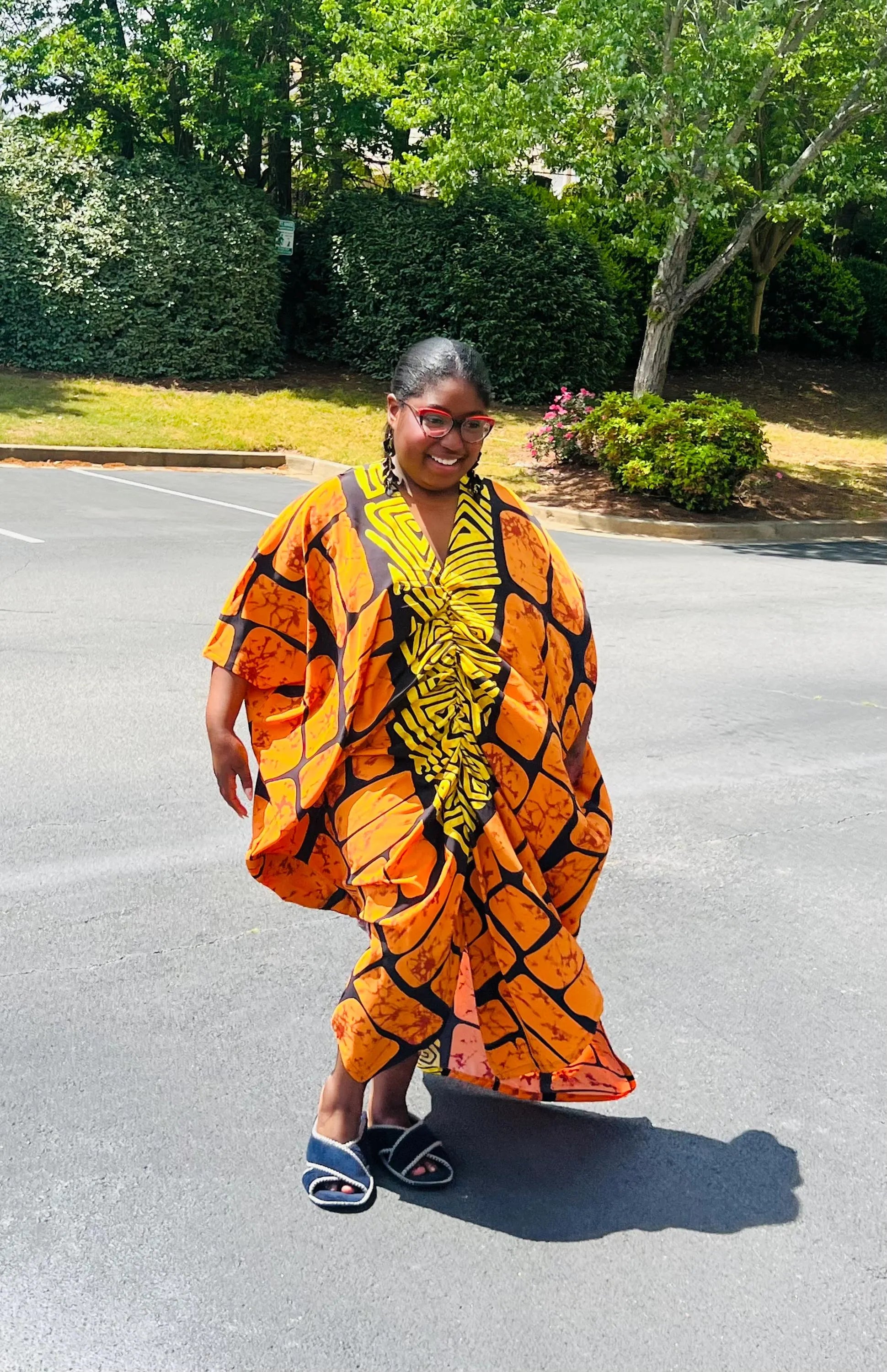 Woman wearing a vibrant, floor-length Ankara Bubu gown with wide sleeves and a relaxed fit, standing outdoors.