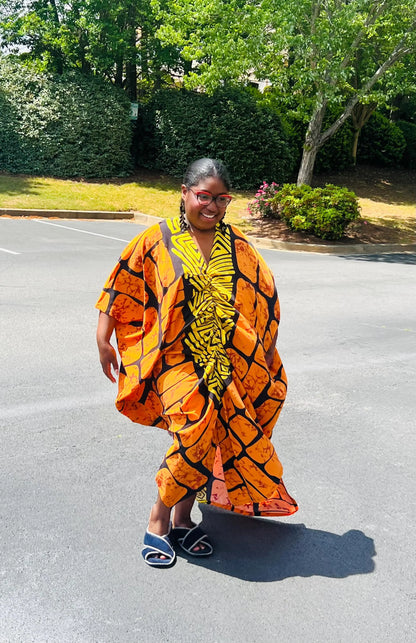 Woman wearing a vibrant, floor-length Ankara Bubu gown with wide sleeves and a relaxed fit, standing outdoors.