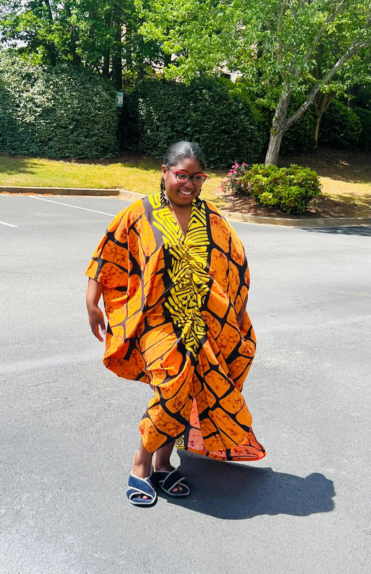 Woman wearing a vibrant, floor-length Ankara Bubu gown with wide sleeves and a relaxed fit, standing outdoors.
