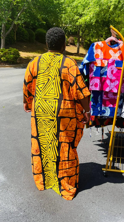 Woman wearing a vibrant, floor-length Ankara Bubu gown with wide sleeves and a relaxed fit, standing outdoors.