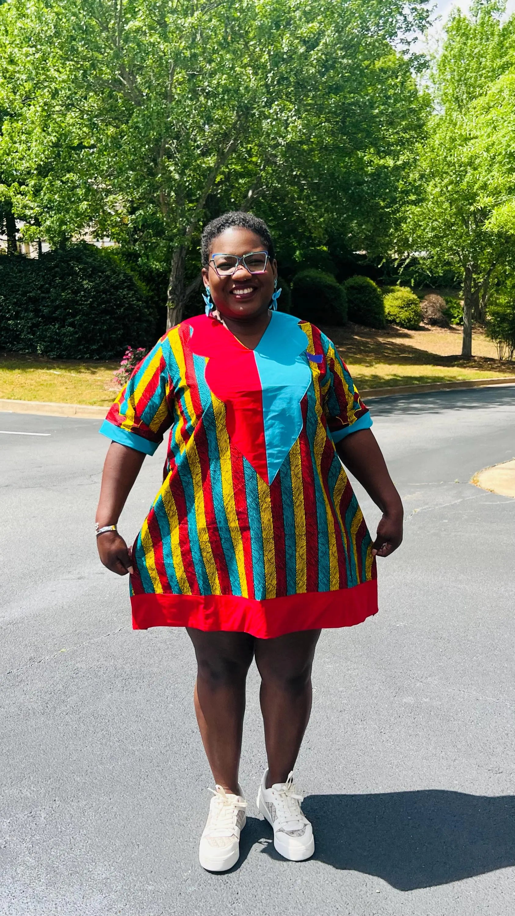 Woman wearing a vibrant African Ankara print mini dress with short sleeves and a flattering A-line silhouette, standing outdoors.