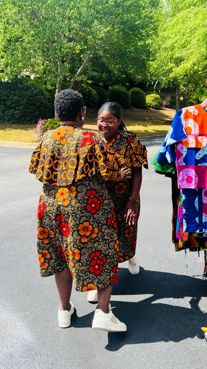 Woman wearing a reversible Ankara dress with open shoulders, ruffled A-line skirt, and front zipper, standing outdoors.